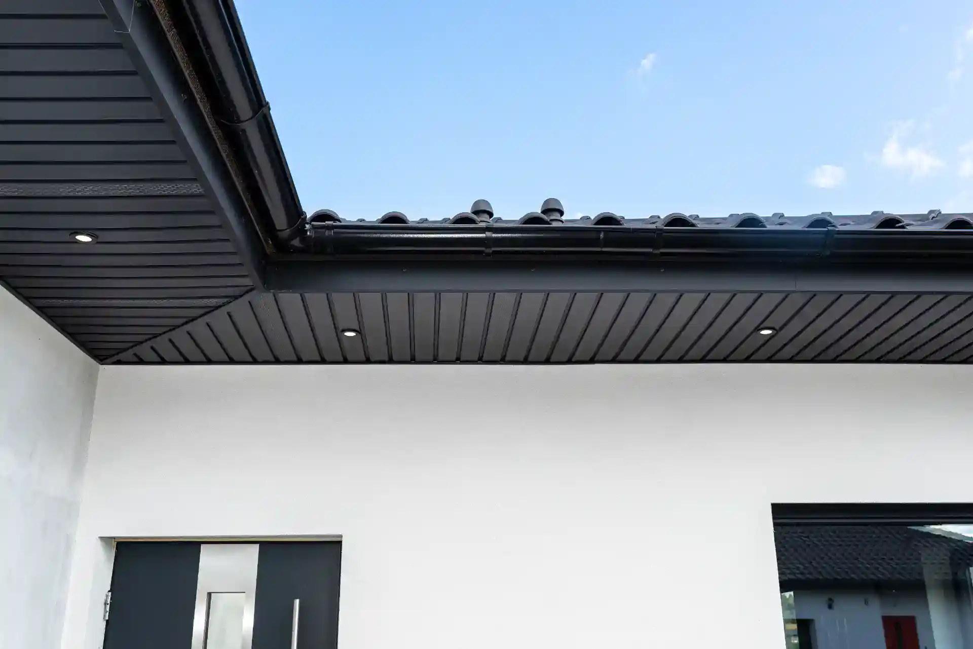 Stilfuldt sort tag med tagrender og træbeklædning til moderne facade.