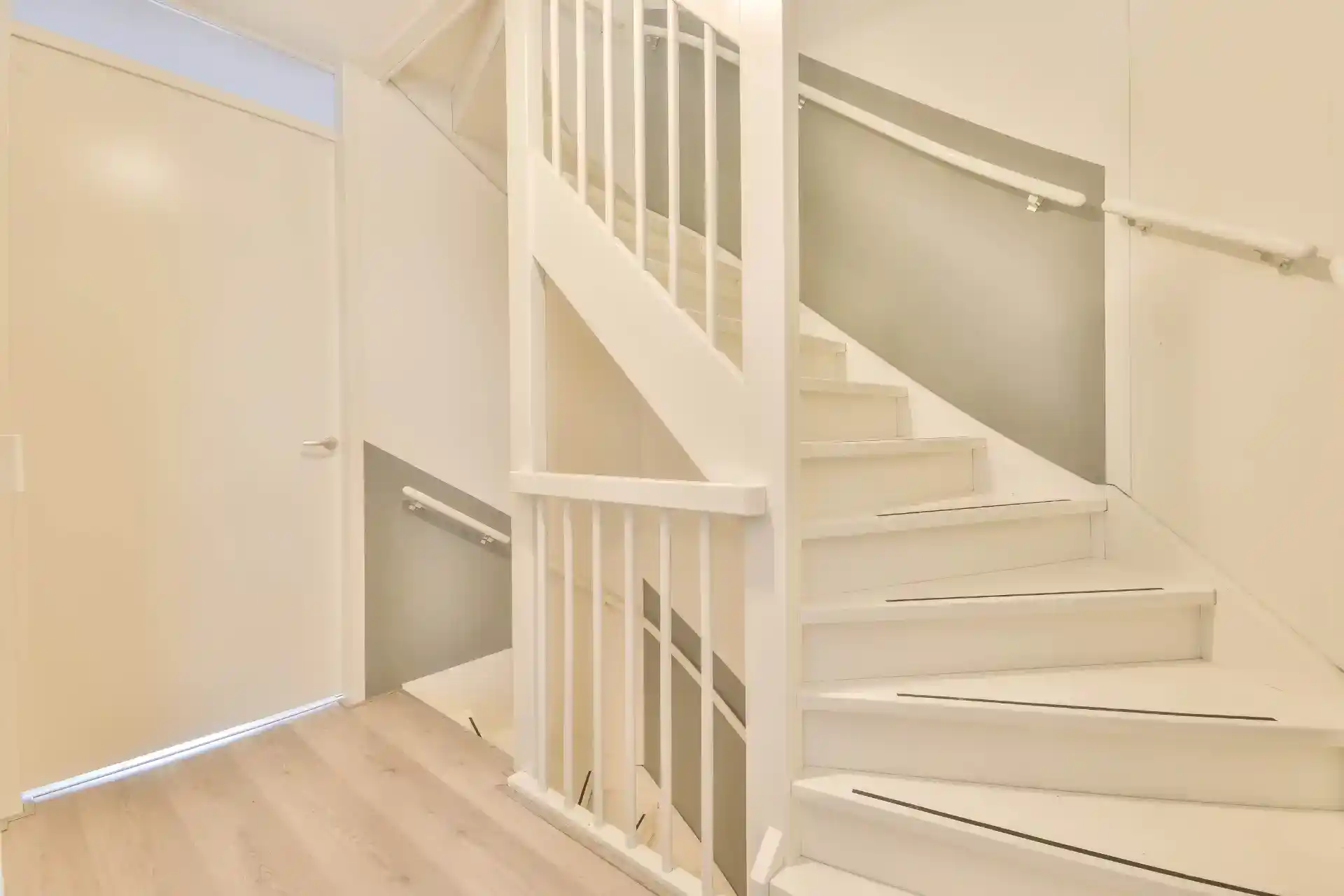 Hvid trappe med gelænder og opbevaringsmuligheder, udført af professionel tømrer i Danmark.