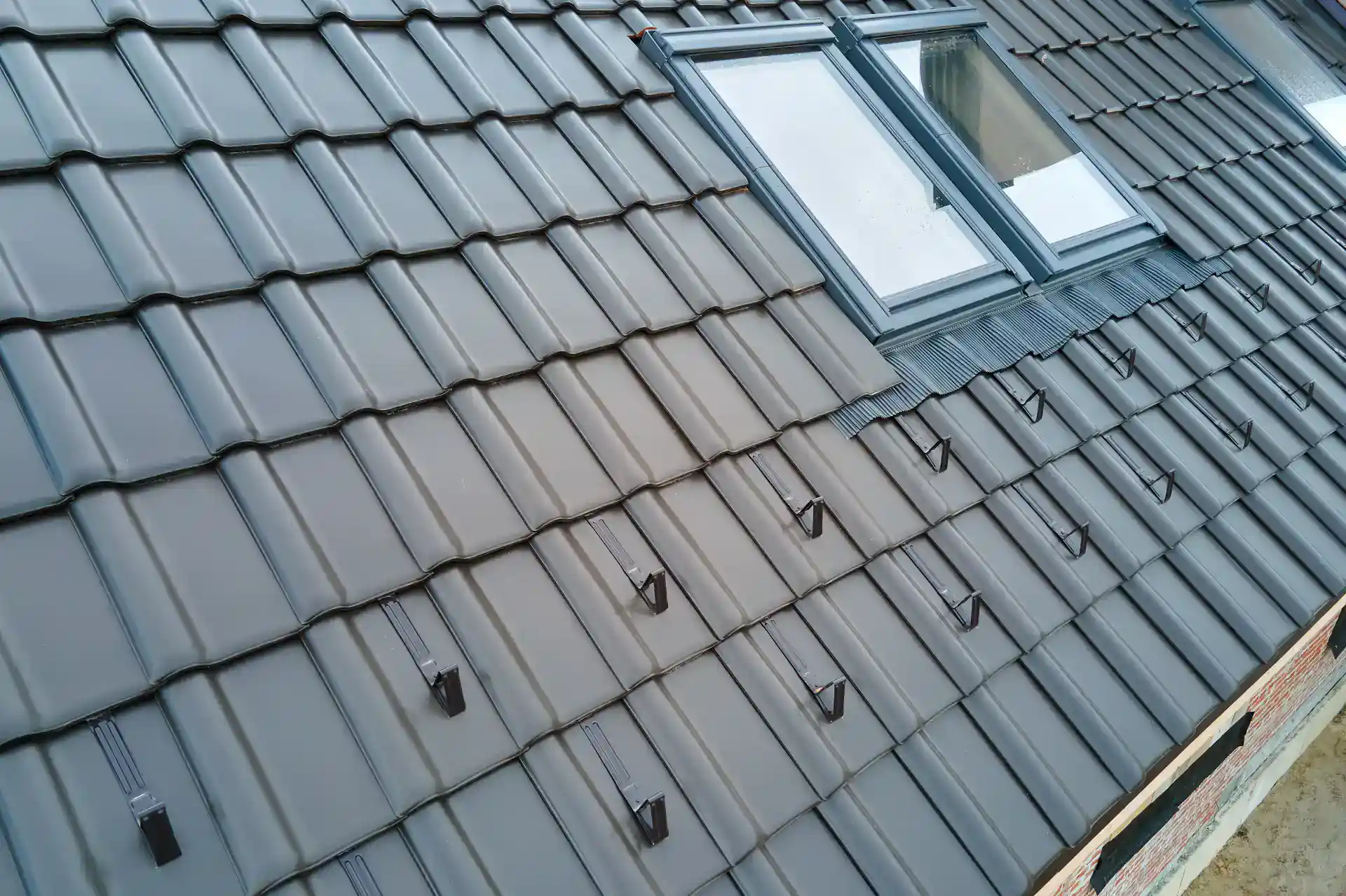 Billedet viser et moderne parcelhus med tagrender og store ovenlys, der sikrer godt lysindfald indendørs.