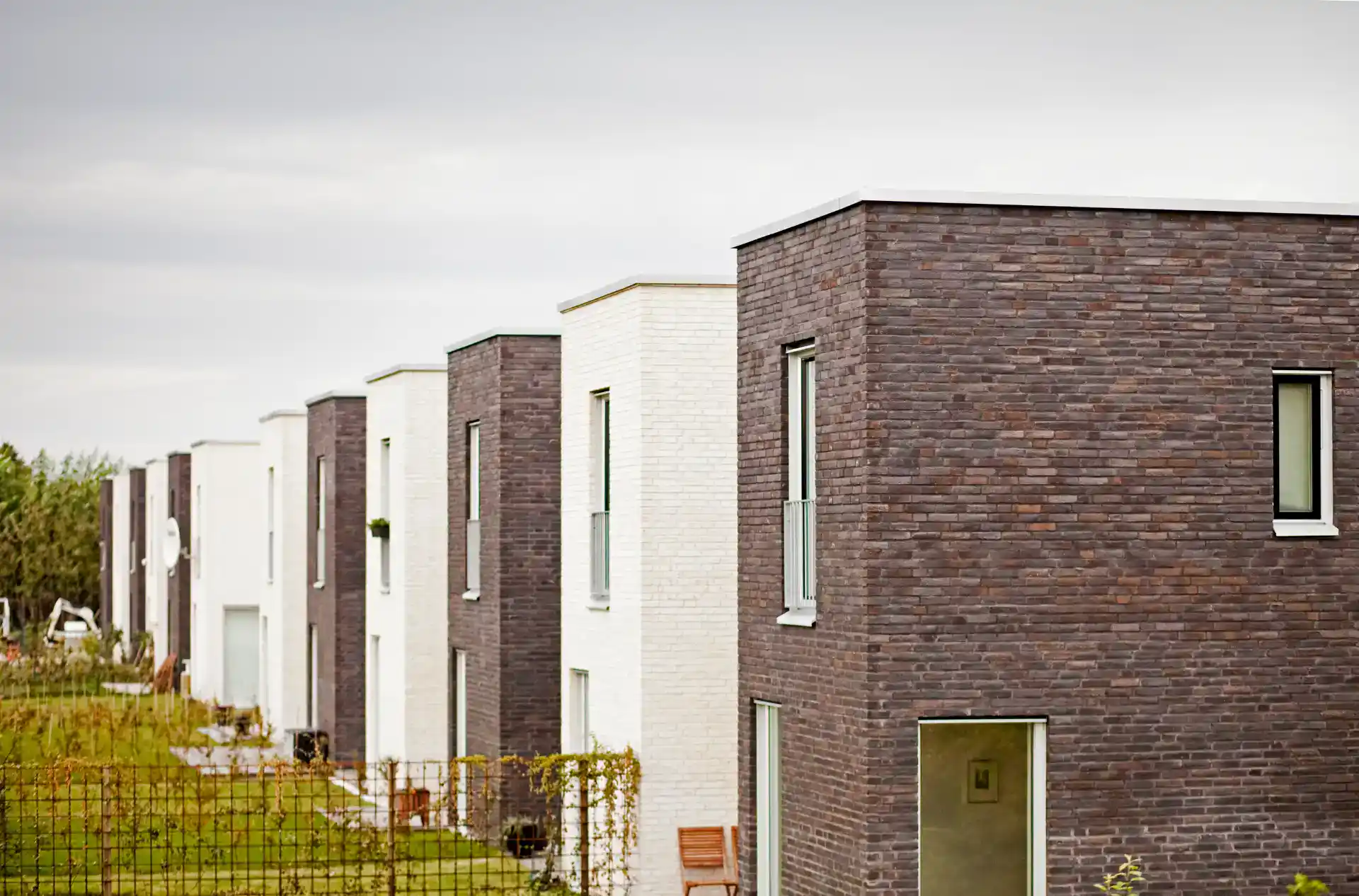 Alt tekst: Moderne træ-huse med forskellige murstensfacader og store vinduer.