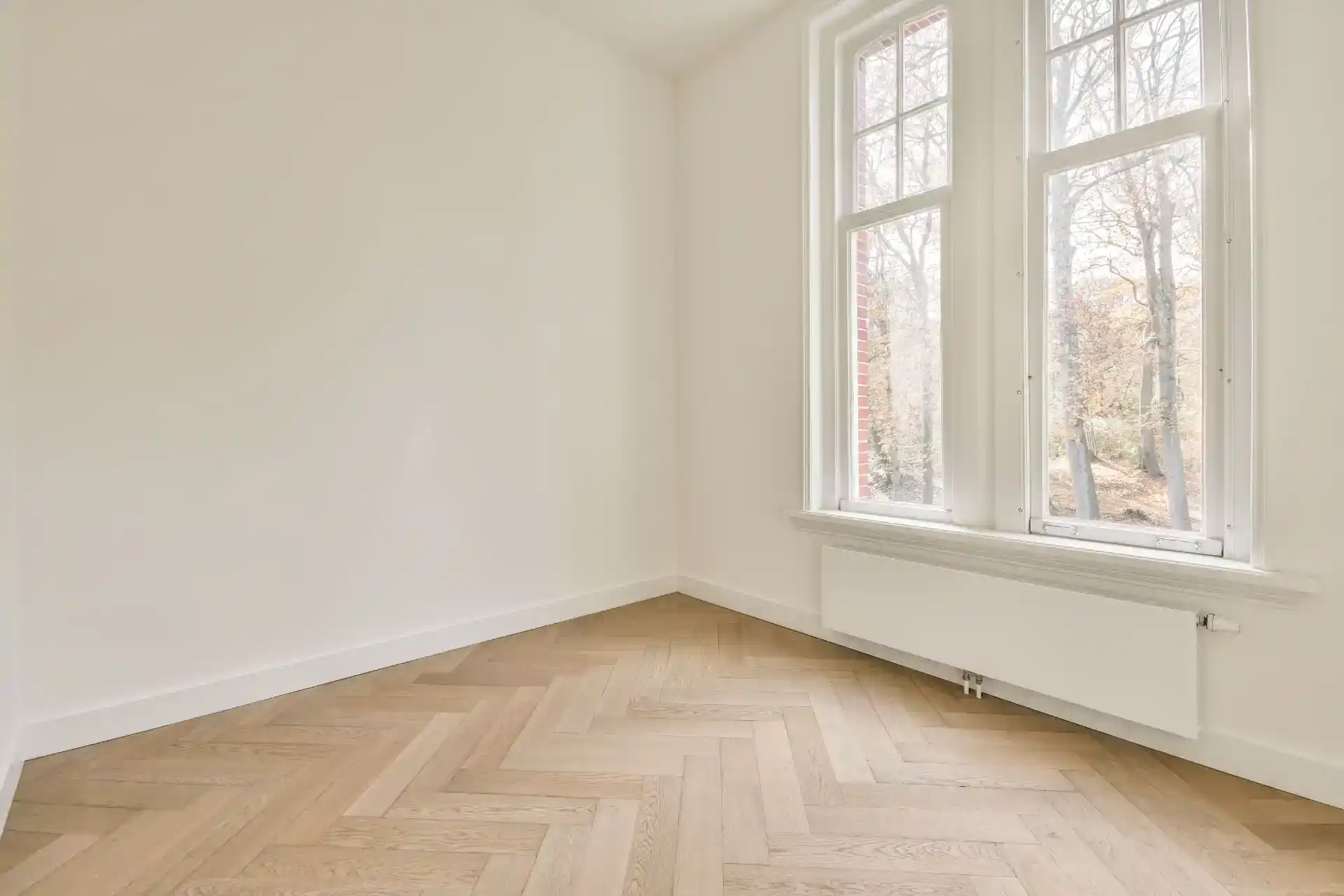 Hvidt værelse med store vinduer og trægulv, professionelt tømrerarbejde i Dit hjem.