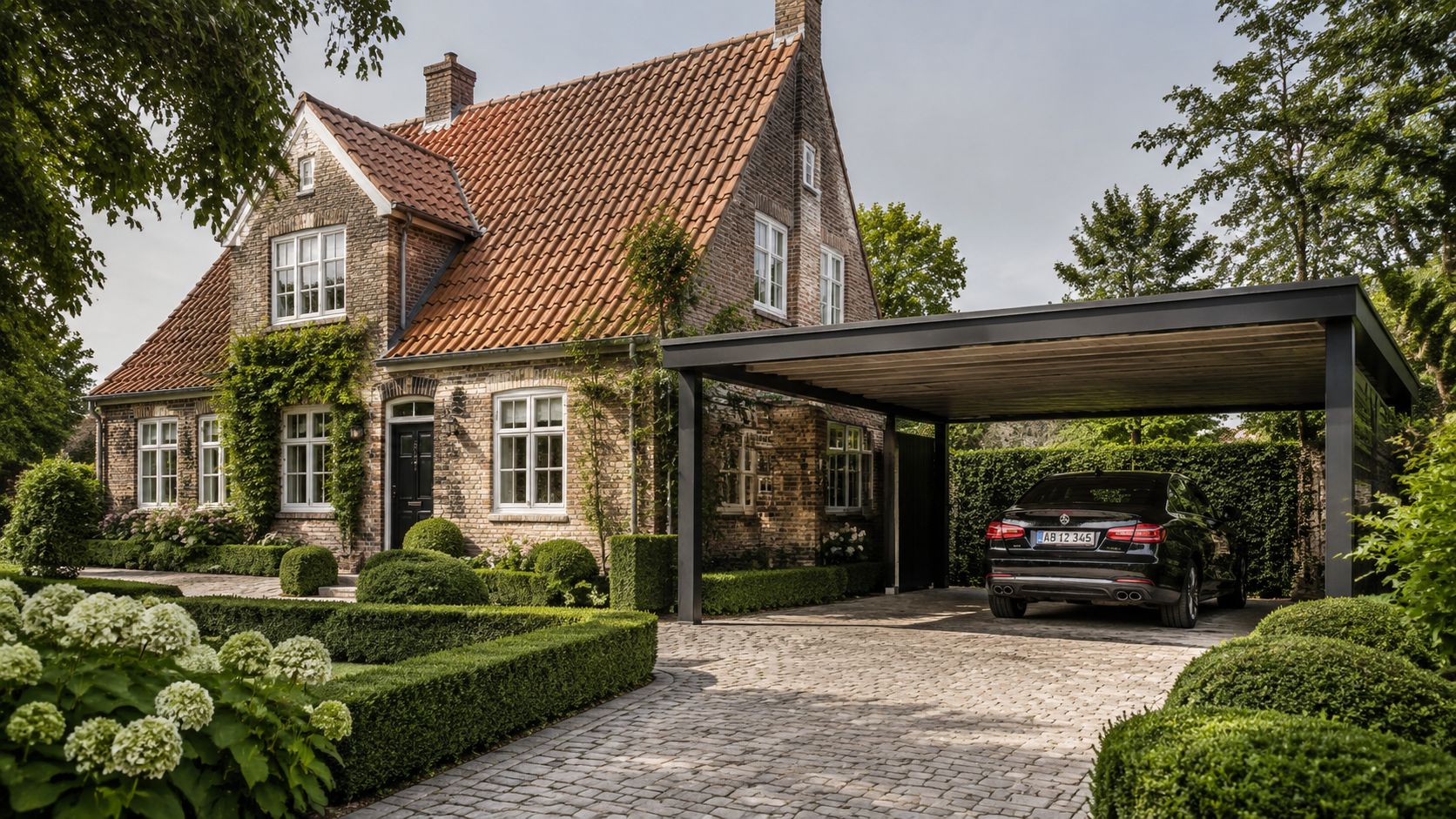 Et smukt murstenshus med en moderne sort stål-carport og en velplejet have med buksbomhække og hortensiaer.